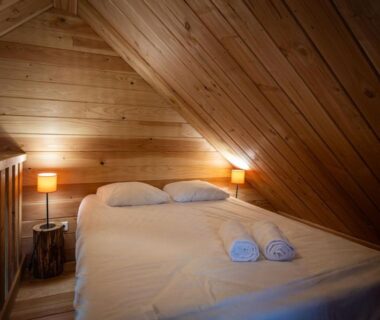 Chambre mansardée en bois avec lit et serviettes dans le camping Huttopia Font Romeu