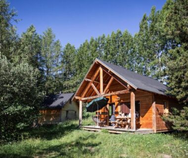 Chalet en bois sur pelouse entouré de pins au camping Huttopia Font Romeu