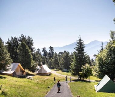Sentier herbeux avec tentes et sapins au camping Huttopia Font Romeu