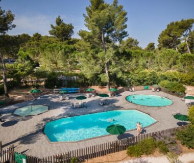 Piscines extérieures entourées de pins au camping Huttopia Fontvieille