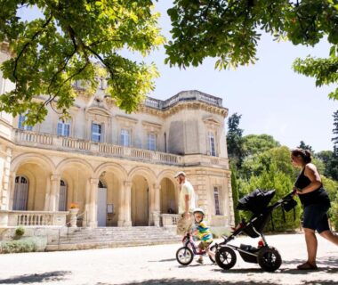 Allée ombragée devant villa avec poussette et enfant au Huttopia Fontvieille
