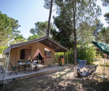 Terrasse de tente et coin repas sous les pins au camping Huttopia Fontvieille