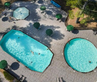 Zone piscine avec deux bassins et parasols au camping Huttopia Fontvieille