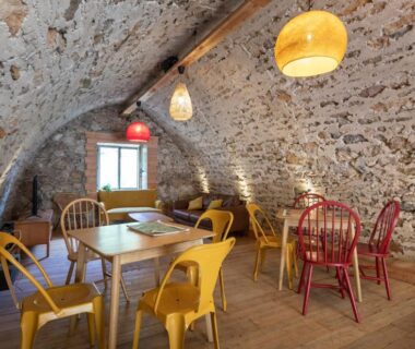 Salle voûtée avec tables et chaises colorées dans le camping Huttopia Gorges du Tarn