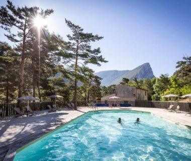 Piscine extérieure entourée de pins et montagnes au camping Huttopia Gorges du Verdon