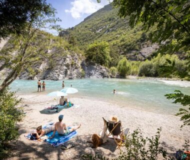 Rive du Verdon avec plage de galets et baigneurs au camping Huttopia Gorges du Verdon