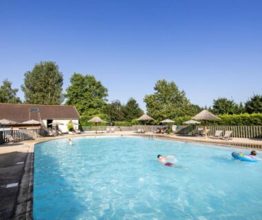 Piscine extérieure avec transats et parasols au camping Huttopia La Plage Blanche