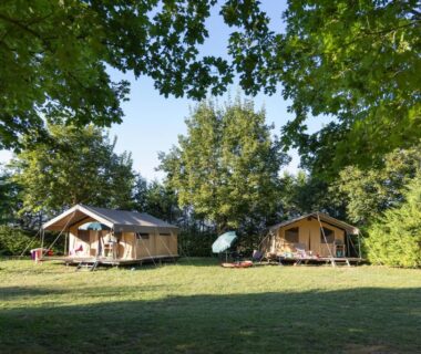 Prairie ombragée avec deux tentes lodge au Huttopia La Plage Blanche