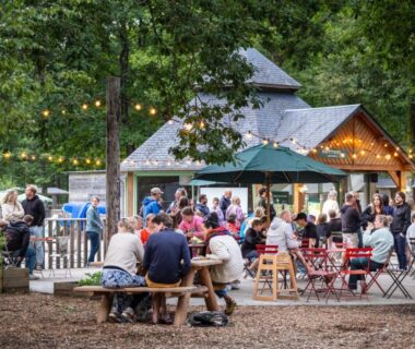 Terrasse extérieure avec tables et guirlandes lumineuses au Huttopia Lac de Sillé
