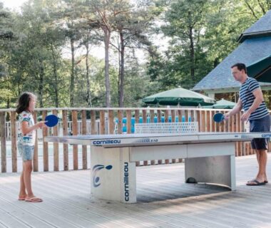 Terrasse bois avec table de ping-pong et deux joueurs au Huttopia Lac de Sillé