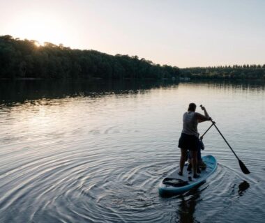 Sur le lac une personne en paddle au coucher du soleil au Huttopia Lac de Sillé