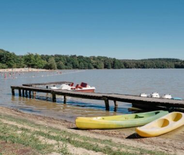Plage sableuse et ponton avec kayaks au camping Huttopia Lac de Sillé