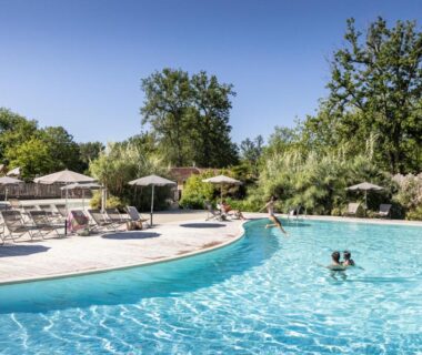 Piscine extérieure avec parasols et transats au Huttopia Lac de l'Uby