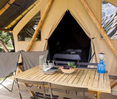 Terrasse en bois avec table et tente glamping au Huttopia Lac de l'Uby – Gers