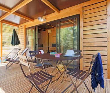 Terrasse en bois avec table et chaises du lodge Huttopia Lac de l'Uby Gers