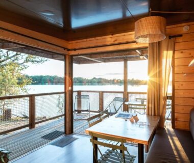 Terrasse couverte donnant sur le lac avec table et chaises au Huttopia Lac de l'Uby
