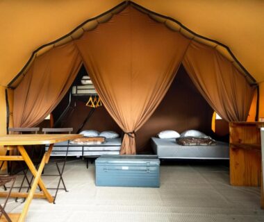 Intérieur de tente avec deux lits et mobilier au Huttopia Lac de l'Uby