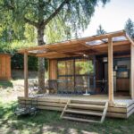 Terrasse couverte avec salon extérieur au chalet en bois Huttopia Lac de la Siauve