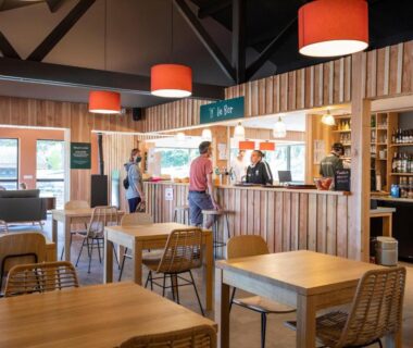 Salle bar avec comptoir tables et luminaires du Huttopia Lac de la Siauve
