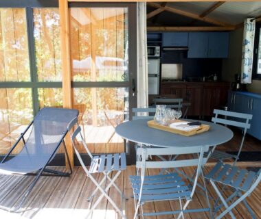 Terrasse couverte avec table et chaises dans l'hébergement Huttopia Lac de la Siauve
