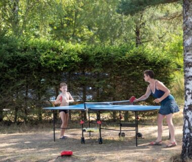 Espace extérieur avec table de ping-pong et joueurs au camping Huttopia Lac de la Siauve