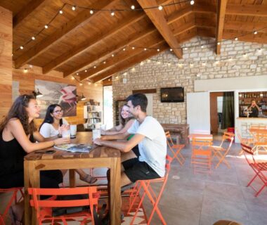 Salle commune avec table et chaises orange au camping Huttopia Le Moulin