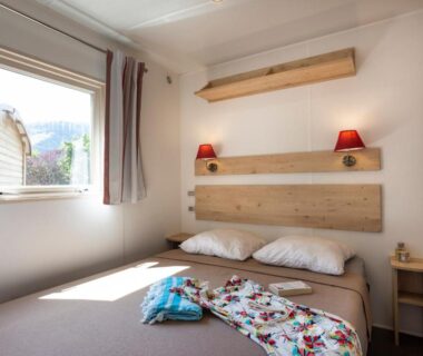 Chambre avec lit double et fenêtre dans le Huttopia Le Moulin