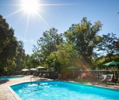 Piscine extérieure sur terrasse en bois avec transats au camping Huttopia Le Moulin