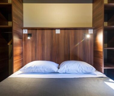 Chambre intérieure avec tête de lit en bois et lit double au Huttopia Les Châteaux