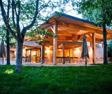 Terrasse extérieure éclairée sous arbres au camping Huttopia Les Châteaux