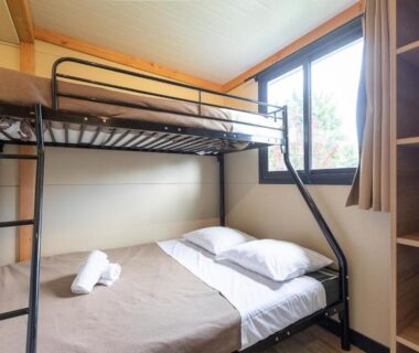 Dans la chambre avec lits superposés et fenêtre au Huttopia Les Châteaux