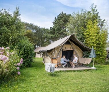 Terrasse de tente safari dans un jardin verdoyant au camping Huttopia Les Falaises