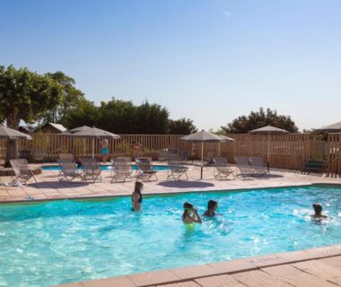 Piscine extérieure avec enfants et transats au camping Huttopia Meursault