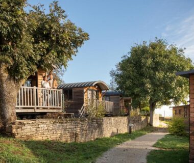 Sentier bordé de roulottes et chalets en bois au Huttopia Meursault
