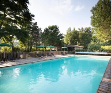 Piscine extérieure bordée d'arbres au Huttopia Millau