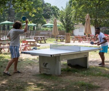 Espace jeux avec table de ping-pong et bancs au camping Huttopia Millau