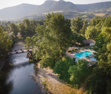 Bord de rivière avec piscine et transats au camping Huttopia Millau