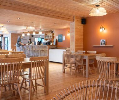 Salle commune avec tables et chaises en bois du Huttopia Pays de Cordes sur Ciel