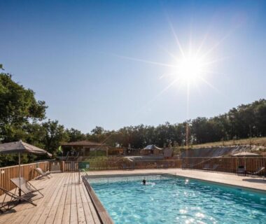 Piscine extérieure et solarium sur terrasse en bois au camping Huttopia Pays de Cordes sur Ciel