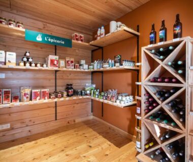 Épicerie intérieure avec étagères de produits et casier à vins au Huttopia Pays de Cordes sur Ciel
