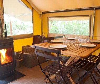 Intérieur de tente avec table à manger et poêle au camping Huttopia Rambouillet