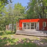 Dans les bois bungalow rouge avec terrasse au Huttopia Royat