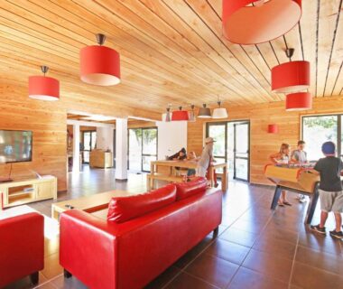 Salle commune avec canapés rouges et table de ping-pong au Huttopia Royat