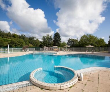 Piscine extérieure avec bassin circulaire et solarium au camping Huttopia Royat
