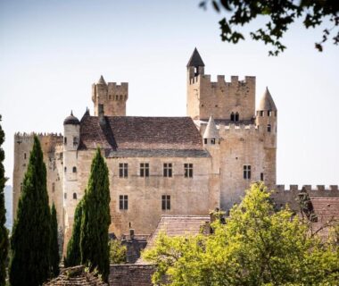 Château médiéval entouré de cyprès vu depuis le camping Huttopia Sarlat
