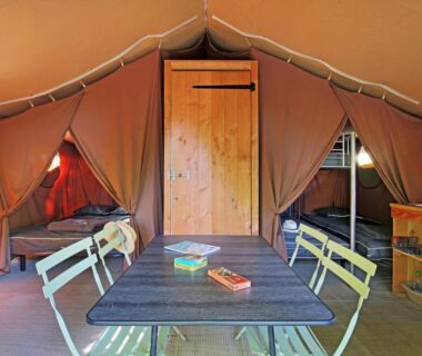 Intérieur de tente avec table et lits aménagés dans Huttopia Sarlat