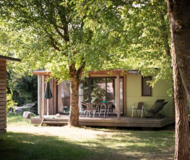 Terrasse en bois ombragée avec chaises devant le mobil-home au Huttopia Saumur