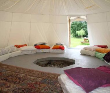 Intérieur de tente ronde avec coussins et foyer central aux Insolites de la Tellerie