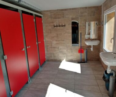 Sanitaires avec cabines rouges et lavabos au camping Insolites de la Tellerie