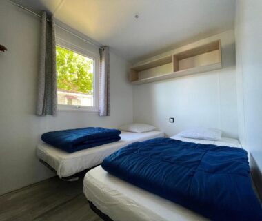 Intérieur chambre avec deux lits et fenêtre au mobil-home International Camping Ardèche